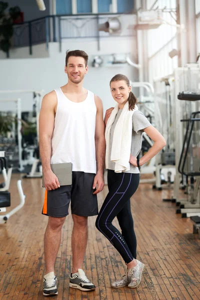 Retrato de una joven pareja deportiva de pie en el gimnasio. — Foto de Stock