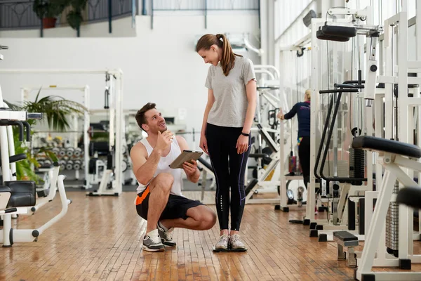 Entrenadora personal y mujer comprobando su progreso. — Foto de Stock