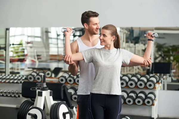 Mujer levantando pesas mientras instructor de fitness ayudándola. — Foto de Stock