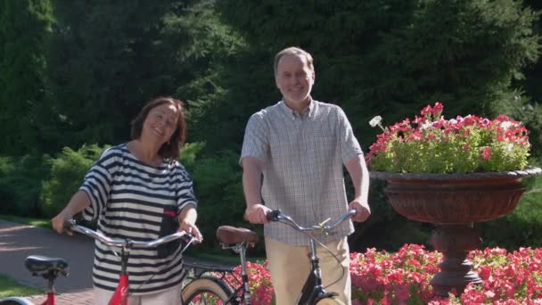 Casal sênior alegre com bicicletas no parque. — Vídeo de Stock