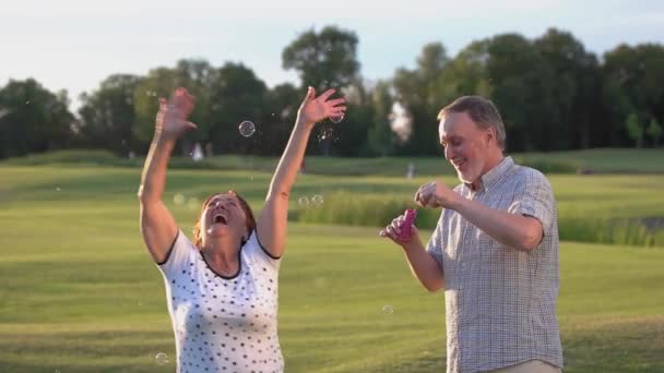 Зрелая пара веселится с пузырьками на открытом воздухе. — стоковое видео