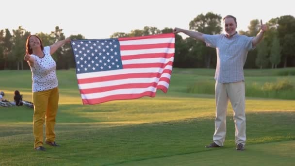 Senior couple with US flag showing thumbs up. — Stock Video