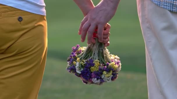 Handen van senioren paar houden bloemen buiten. — Stockvideo