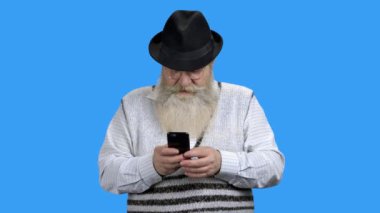 Cep telefonuyla internette sörf yapan yaşlı sakallı adam..