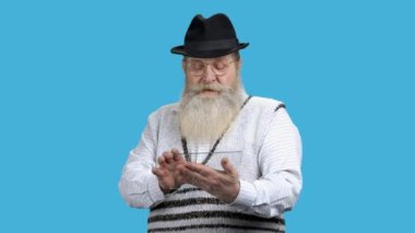 Yaşlı şaşkın adam şeffaf plastik cihaz kullanıyor..