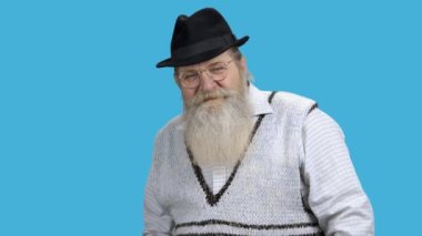 Kıdemli adam kamera ile renkli arka planda konuşuyor..