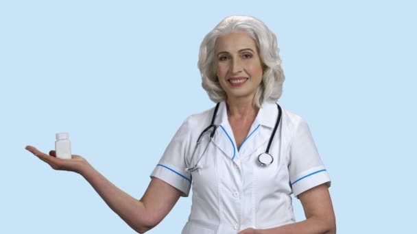 Senior female doctor presenting bottle of pills. — Stock video