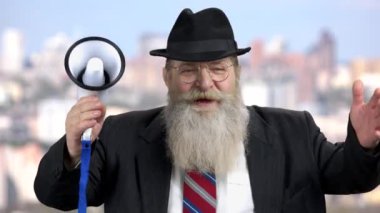 Elinde megafonla kameraya konuşan kıdemli politikacı..