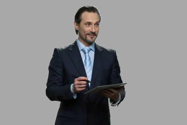 Hombre de negocios guapo haciendo notas en su tableta. — Foto de Stock