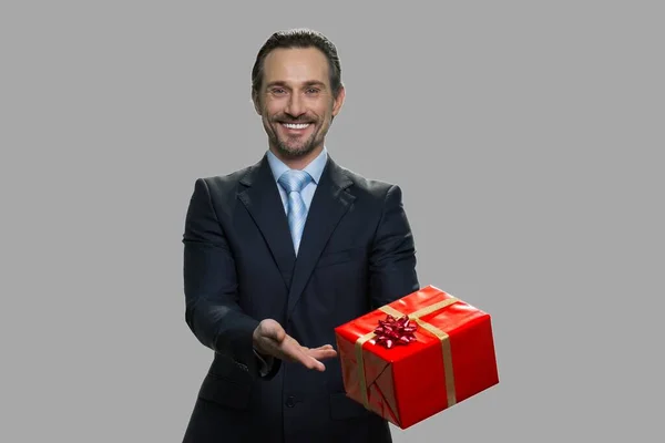 Guapo sonriente hombre de negocios mostrando caja de regalo. — Foto de Stock