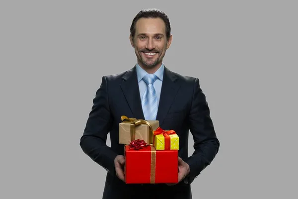 Uomo d'affari caucasico sorridente che tiene scatole regalo. — Foto Stock