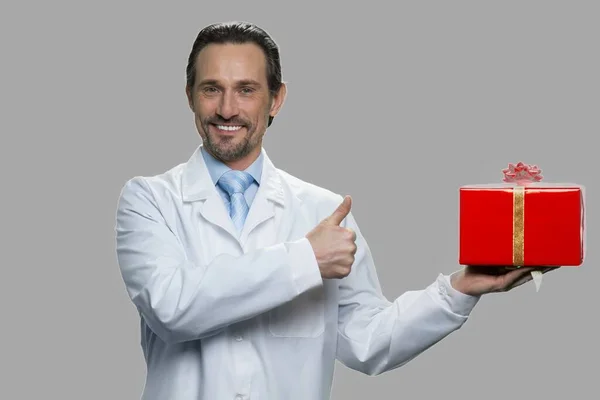 Hombre guapo en abrigo blanco sosteniendo caja de regalo. — Foto de Stock