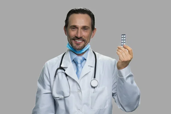 Sonriente médico maduro sosteniendo paquete de pastillas. — Foto de Stock