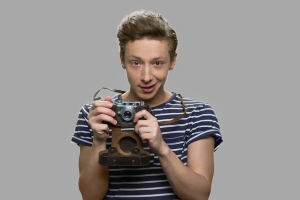 Ragazzo adolescente con fotocamera vintage su sfondo grigio. — Foto Stock