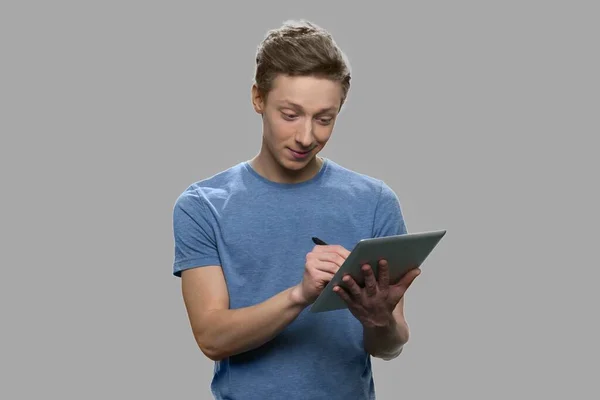 Teenage boy making a note on digital tablet. — Stock Photo, Image