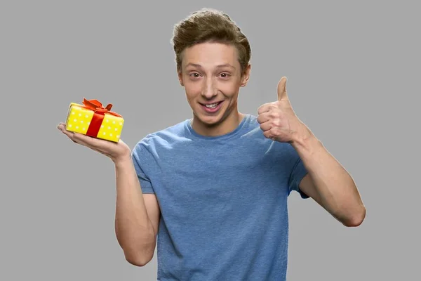 Niño feliz con caja de regalo mostrando el pulgar hacia arriba. — Foto de Stock