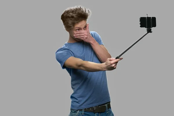 Funny teen boy taking selfie with selfie stick. — Stock Photo, Image