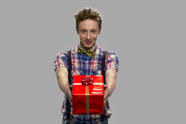 Portrait of teen boy offering gift box. — Stock Photo, Image