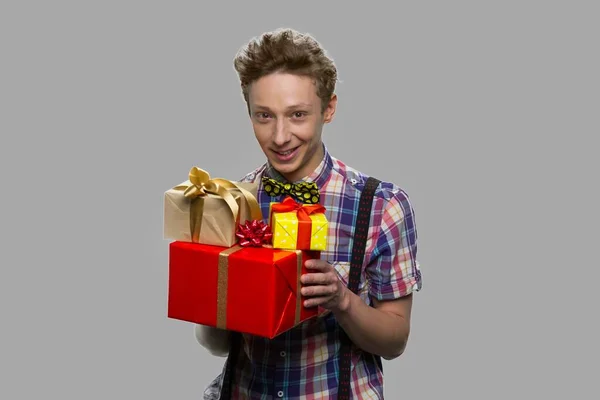 Adolescente cara segurando caixas de presente no fundo cinza. — Fotografia de Stock