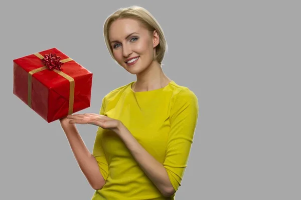 Bella donna che presenta scatola regalo su sfondo grigio. — Foto Stock