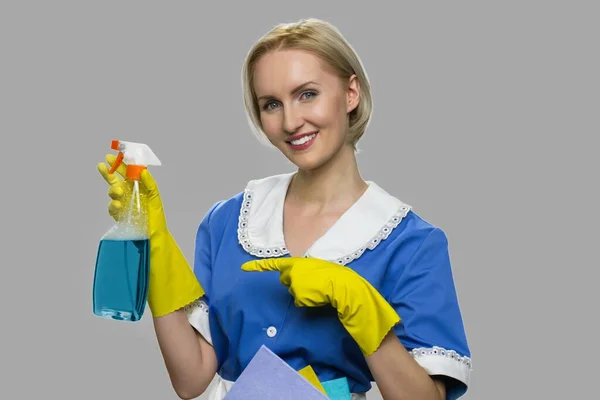 Mulher de limpeza em uniforme apresentando detergente. — Fotografia de Stock