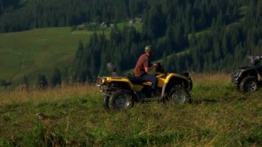 Dağda dört tekerli bisiklete binen üç turist.