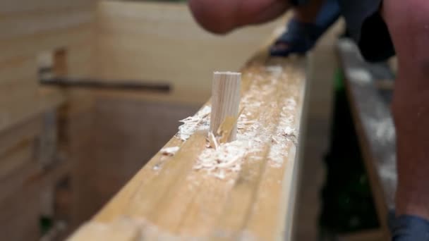 Carpintero martilleo barra de madera para agujero en bloque de madera. — Vídeo de stock