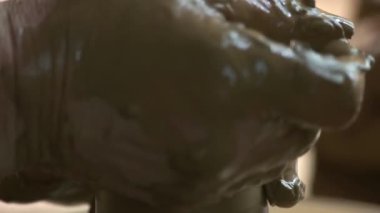 Çamurdan vazo yapan çömlekçinin ellerini kapat.