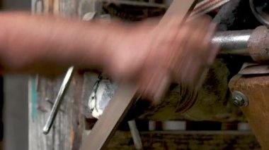 Farrier metal bir aletle at toynağını düzleştiriyor..