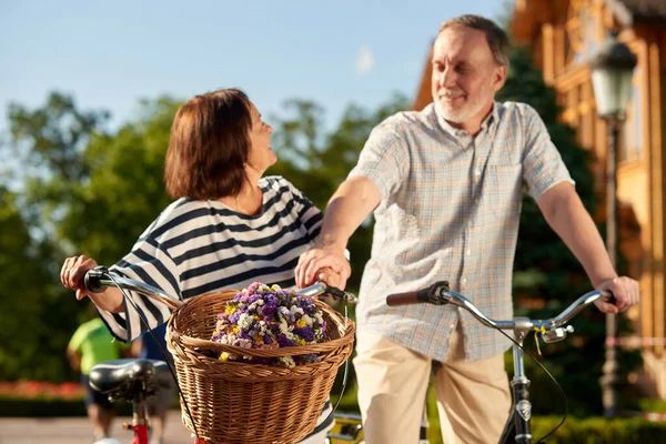 Feliz pareja de ancianos con bicicletas y flores. — Foto de Stock