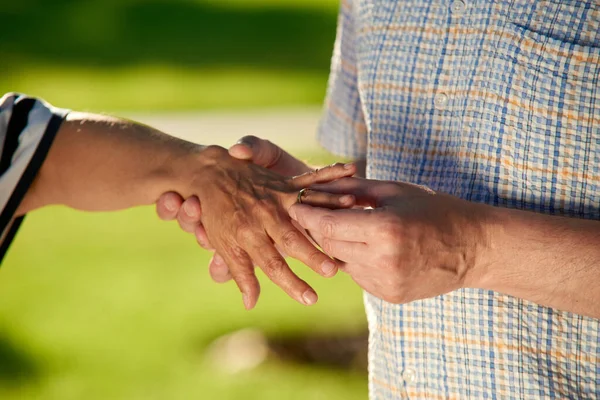 Mature man puts ring on the ring finger of his wife. — Stock Photo, Image