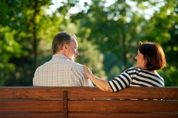 Rückansicht glückliches reifes Paar auf der Bank. — Stockfoto