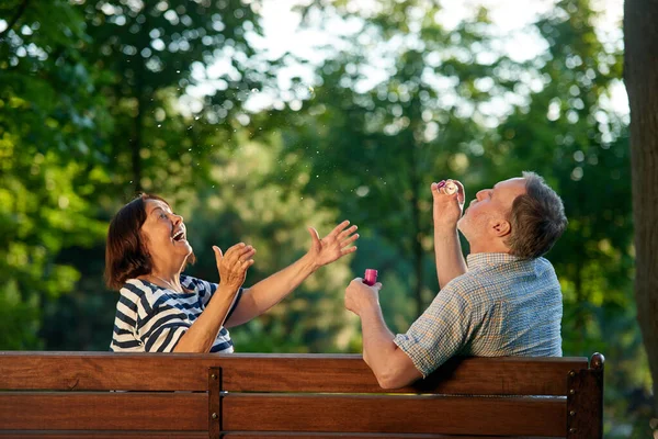 Gelukkig volwassen paar blazen bubbels in het park. — Stockfoto