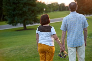 Çiçek buketi ile el ele tutuşan çift.