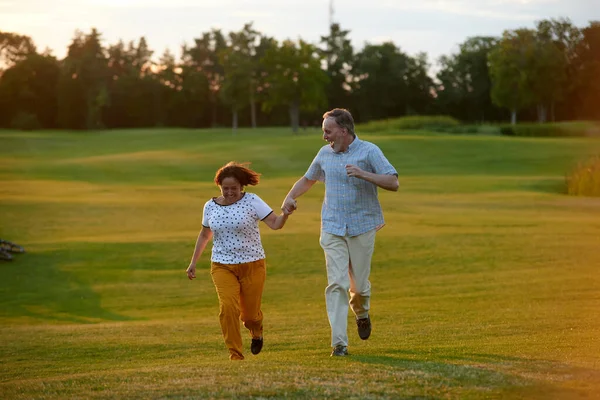 Glücklich lachendes Paar läuft auf den Rasen. — Stockfoto