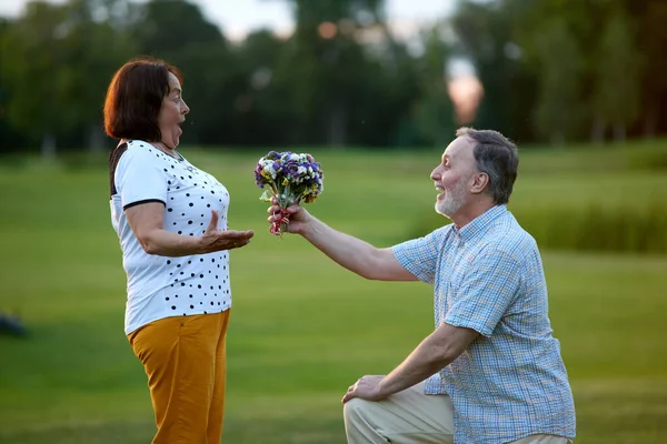 Olgun bir adam heyecanlı karısına çiçek veriyor.. — Stok fotoğraf