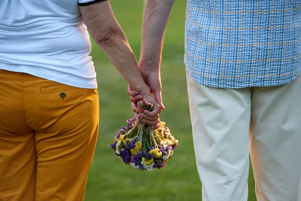 Primer plano pareja cogida de la mano y flores ramo. —  Fotos de Stock