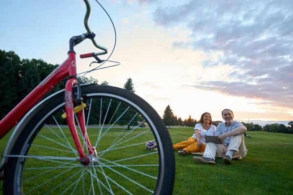 Vélo rouge et couple heureux sur l'herbe. — Photo