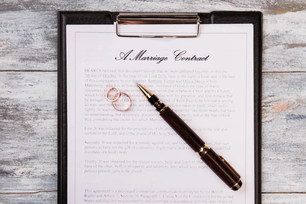Contrato de casamento com caneta e anéis de casamento. — Fotografia de Stock