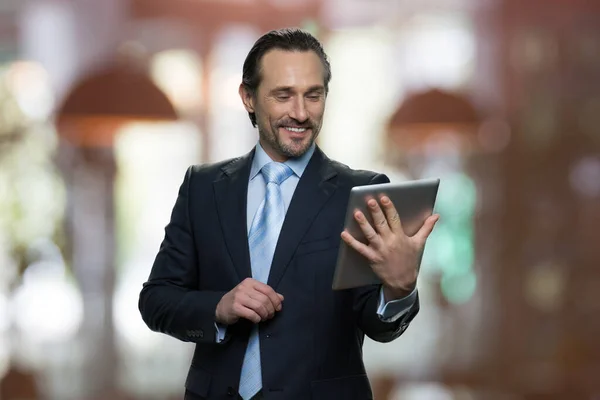 Sorrindo homem de negócios maduro está olhando para tela tablet. — Fotografia de Stock