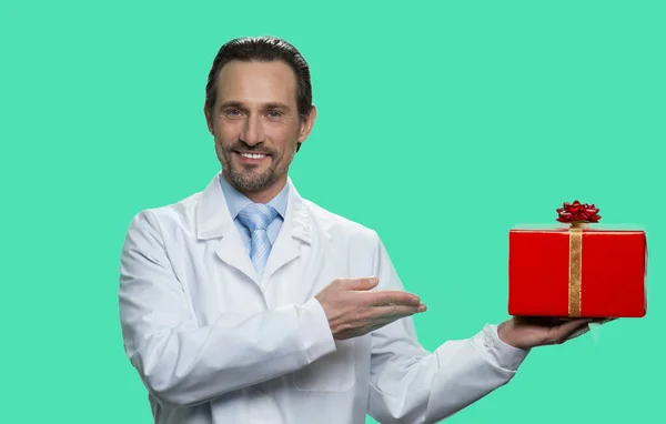 Portrait of mature doctor presenting red gift box. — Stock Photo, Image
