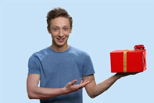 Estudante americano alegre está apresentando caixa de presente vermelho. — Fotografia de Stock