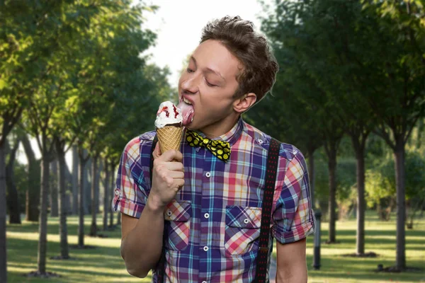 Adolescente americano menino em suspensórios está lambendo sorvete. — Fotografia de Stock