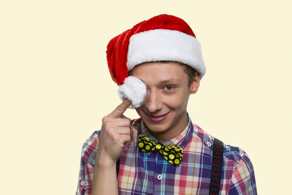 Lächelnder Teenie-Junge schließt die Augen mit Weihnachtsmann-Bommel. — Stockfoto