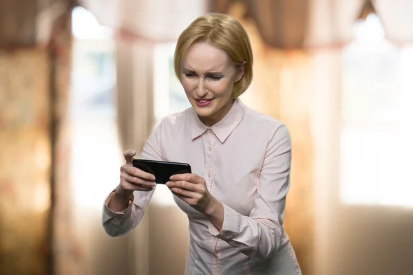 Middle-aged formal-dressed lady is playing video game. — Stock Photo, Image