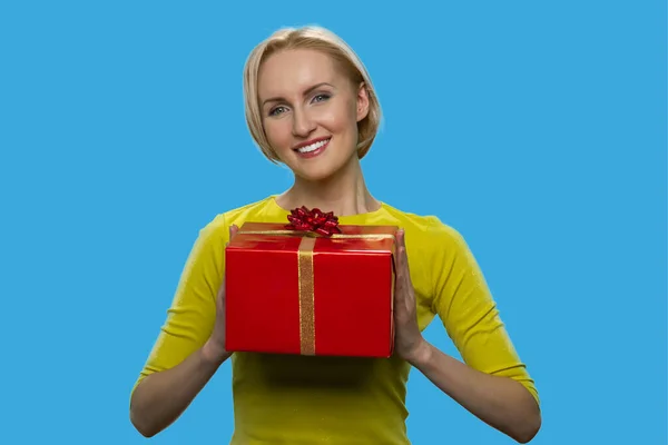 Sorrindo mulher loira está segurando uma caixa de presente vermelha. — Fotografia de Stock