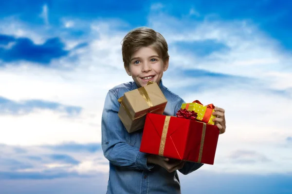 Un niño sonriente sostiene un montón de regalos.. — Foto de Stock