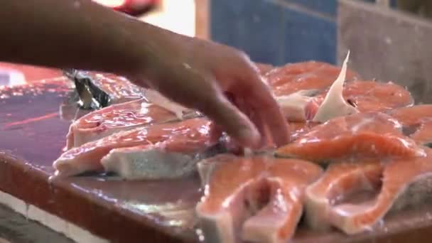 Fechar o homem derramando água em bifes de salmão crus. — Vídeo de Stock