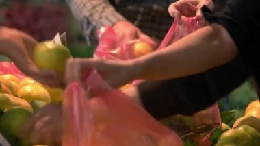 Meyve reyonunda mandalina seçen insanlara yakın çekim.