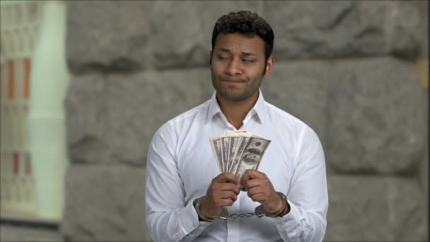 Недовольный бизнесмен в наручниках держит векселя с деньгами. — стоковое видео